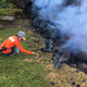 A US Geological Survey geologist in a gas mask collects samples from one of 12 fissures newly opened by Kilauea volcano in Leilani Estates.